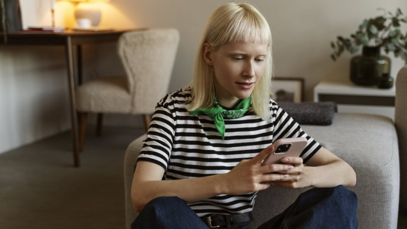 Девушка в гостиной читает с телефона домовой чат